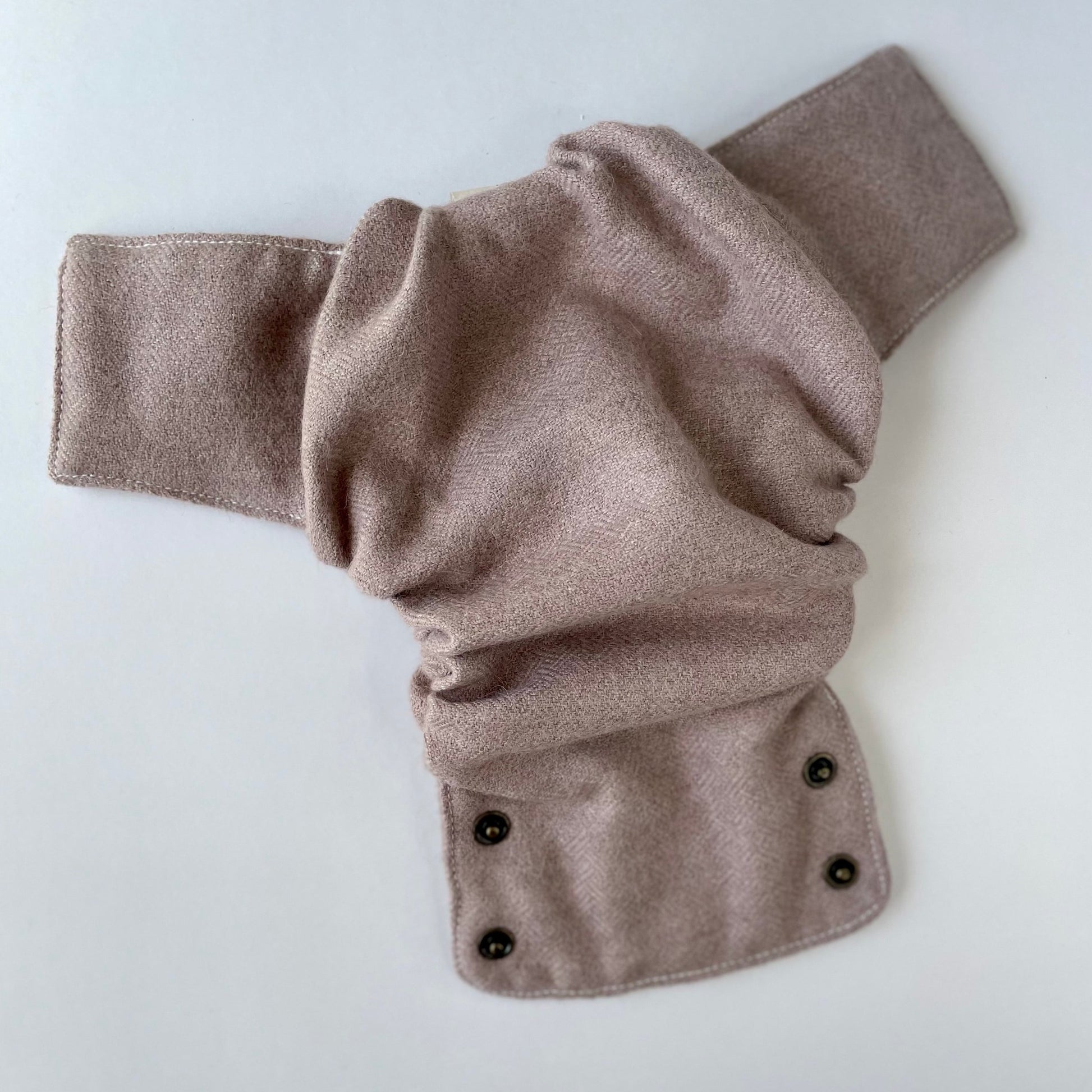 A clay-colored alpaca diaper cover with muted pink tones with a basket weave laying open on a white background.