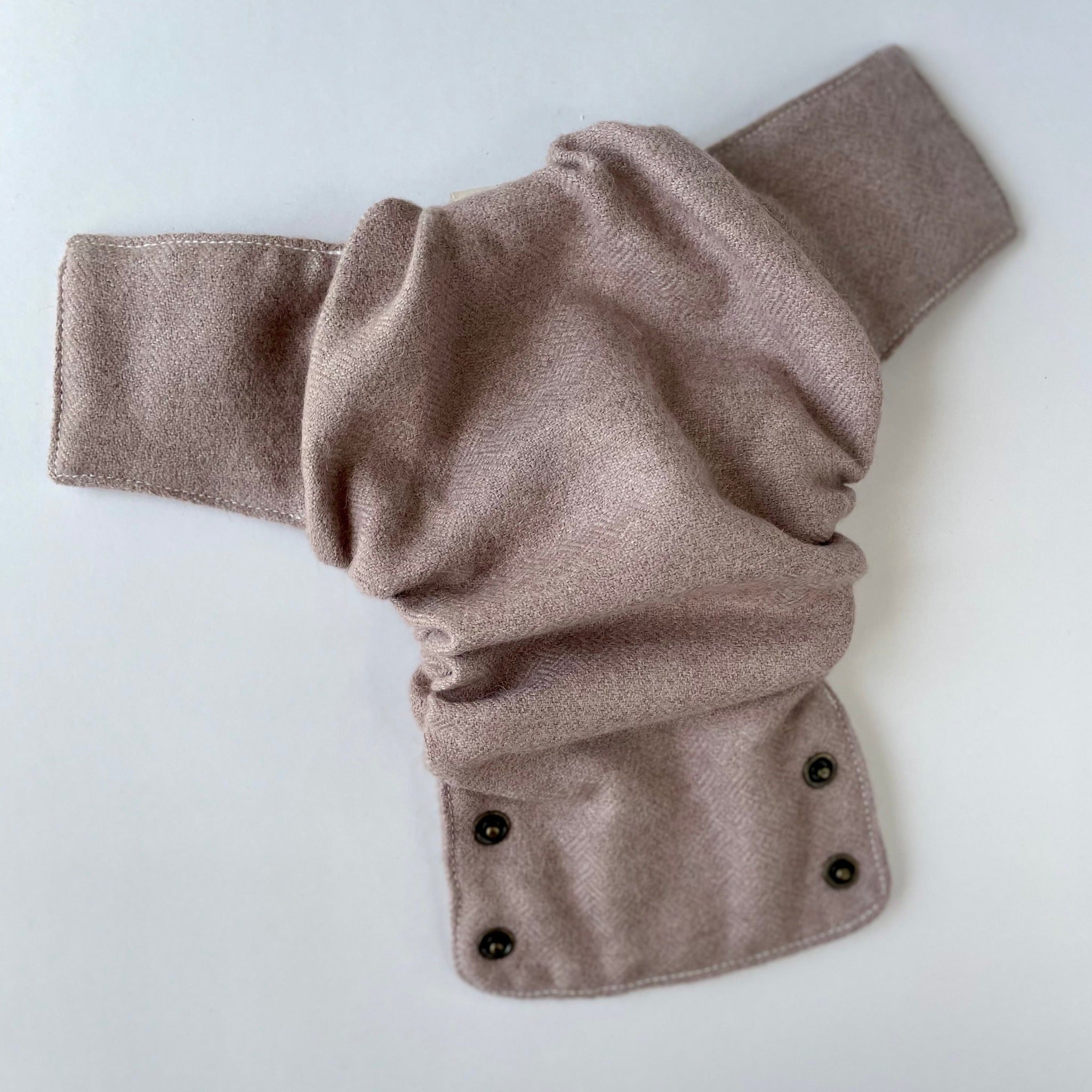 A clay-colored alpaca diaper cover with muted pink tones with a basket weave laying open on a white background.