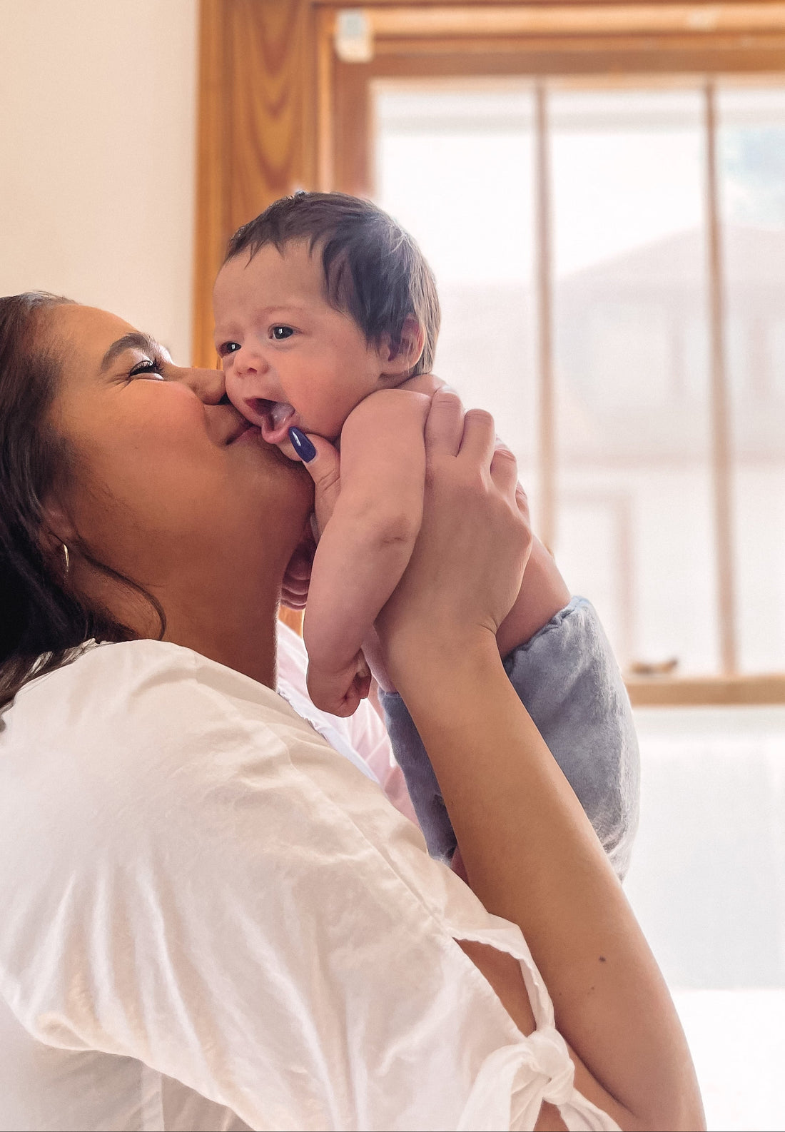 Woman holding a baby close to her face indoors.