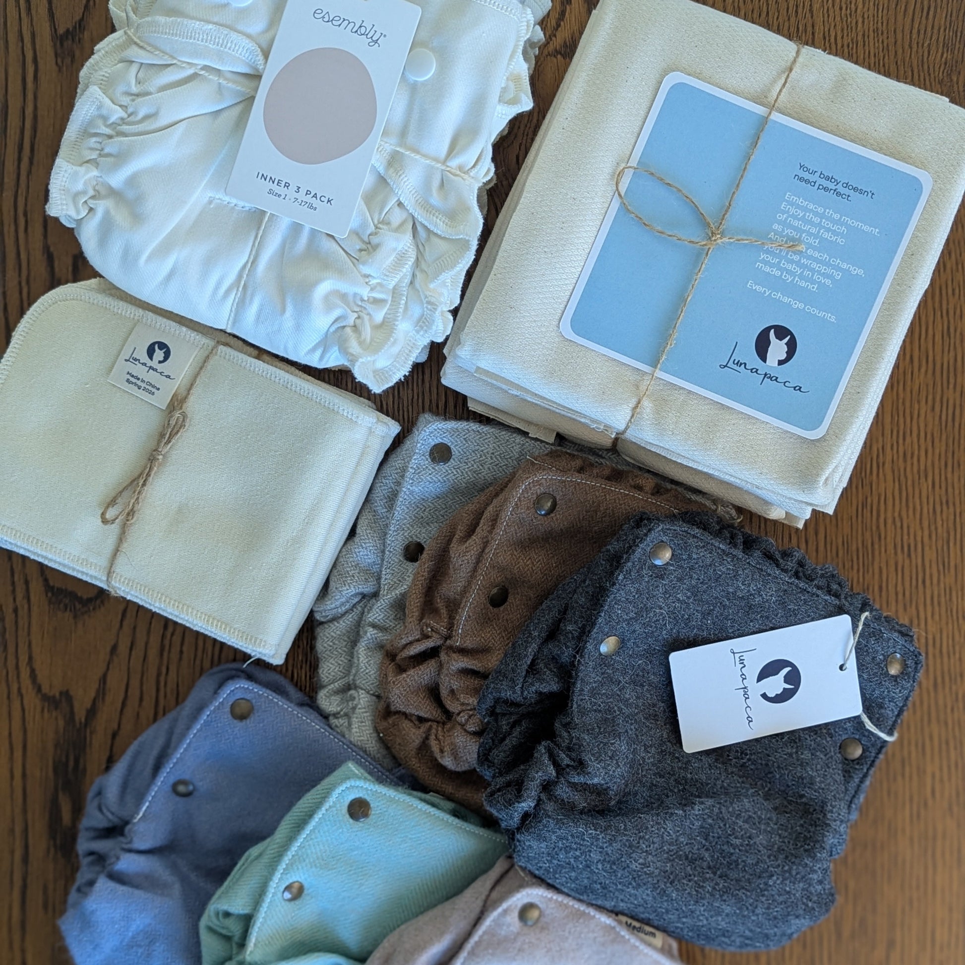 cotton inners, flat diapers, hemp booters, and a variety of alpaca diaper covers in a mix of colors on a wooden table.