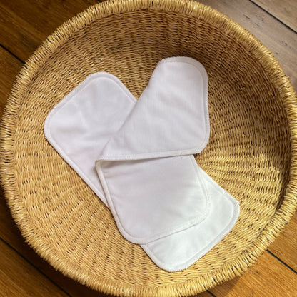 Pair of flat white inserts made from organic cotton and hemp placed inside a basket